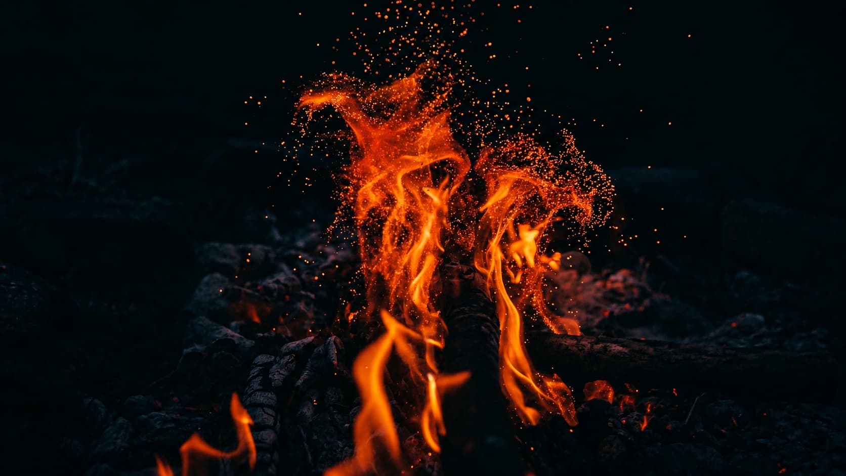 Leuchtende Flammen und feine Funken vor dunklem Hintergrund